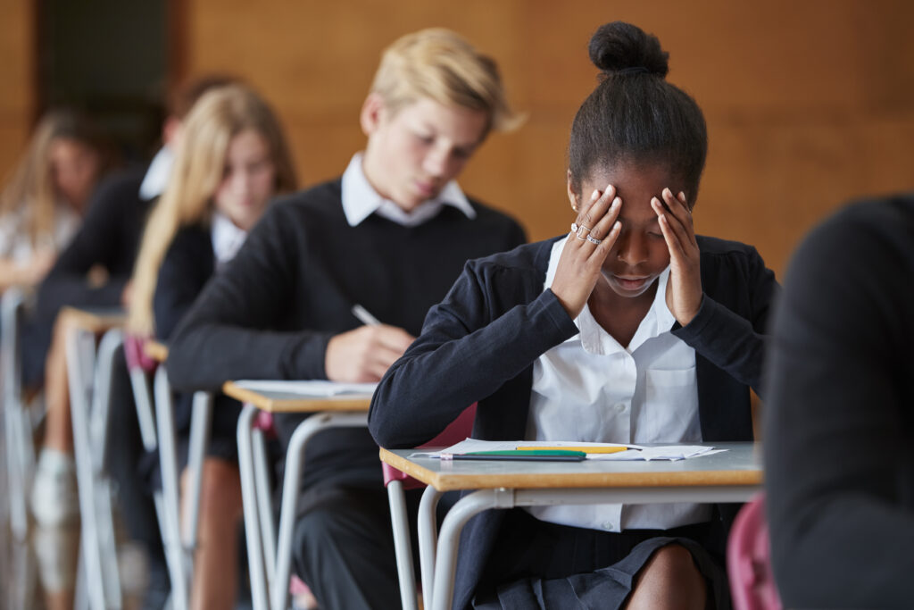 Stressed female student sitting at a classroom desk with head in hands